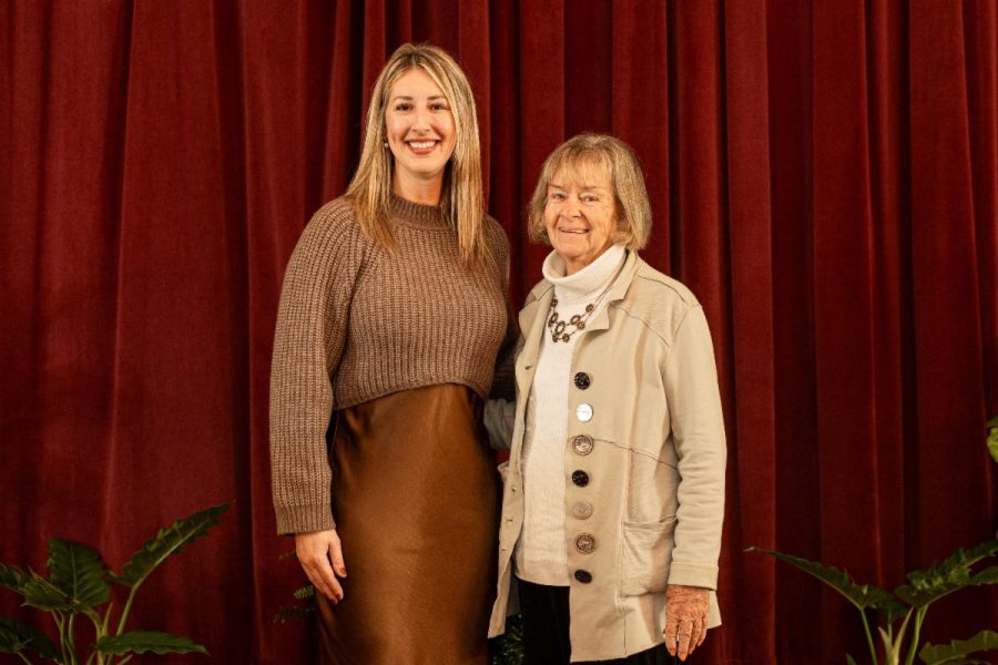 coffin and romig posing for photos in front of a red curtain